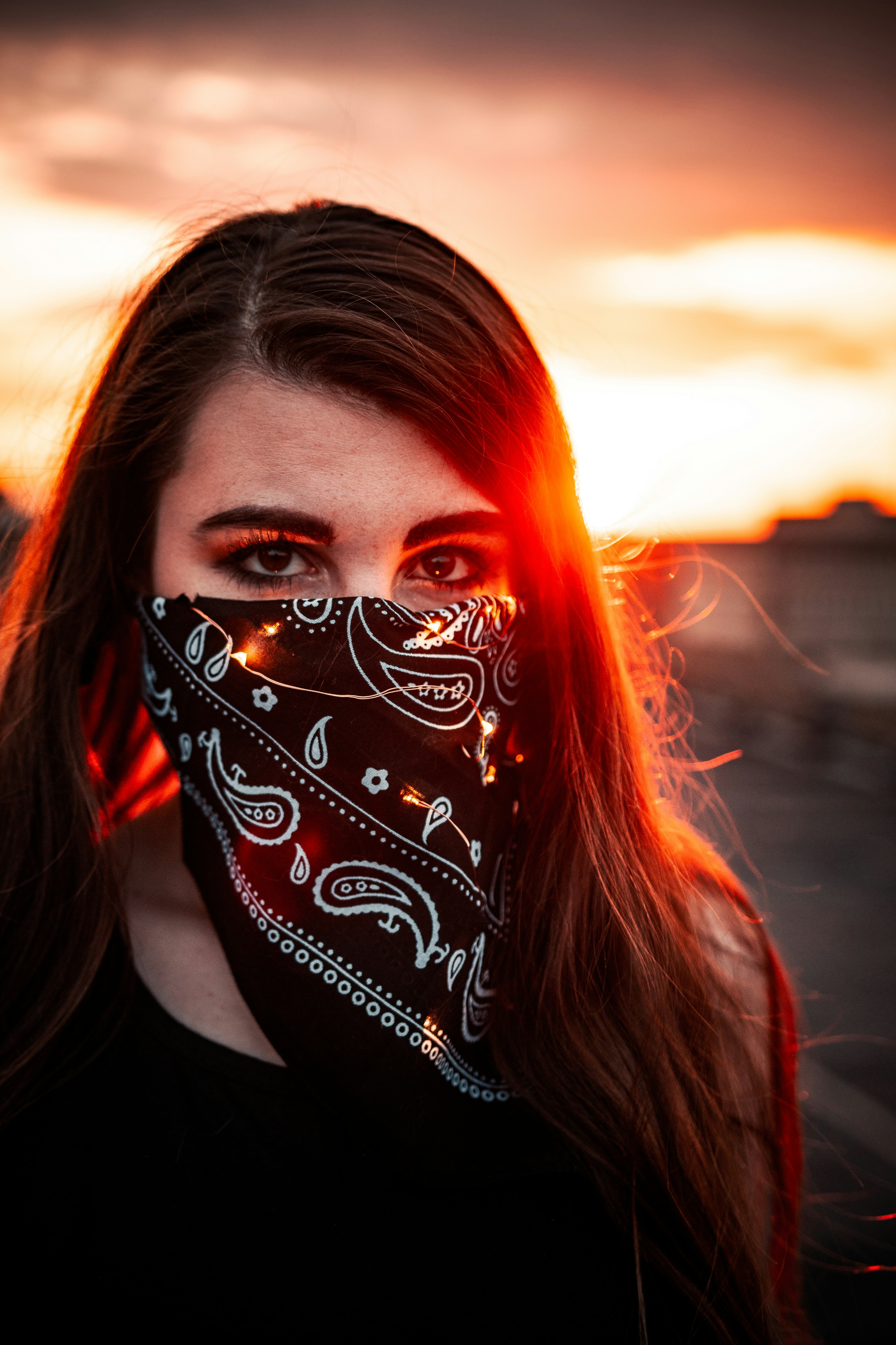 woman with red hair covering face with black and white face mask